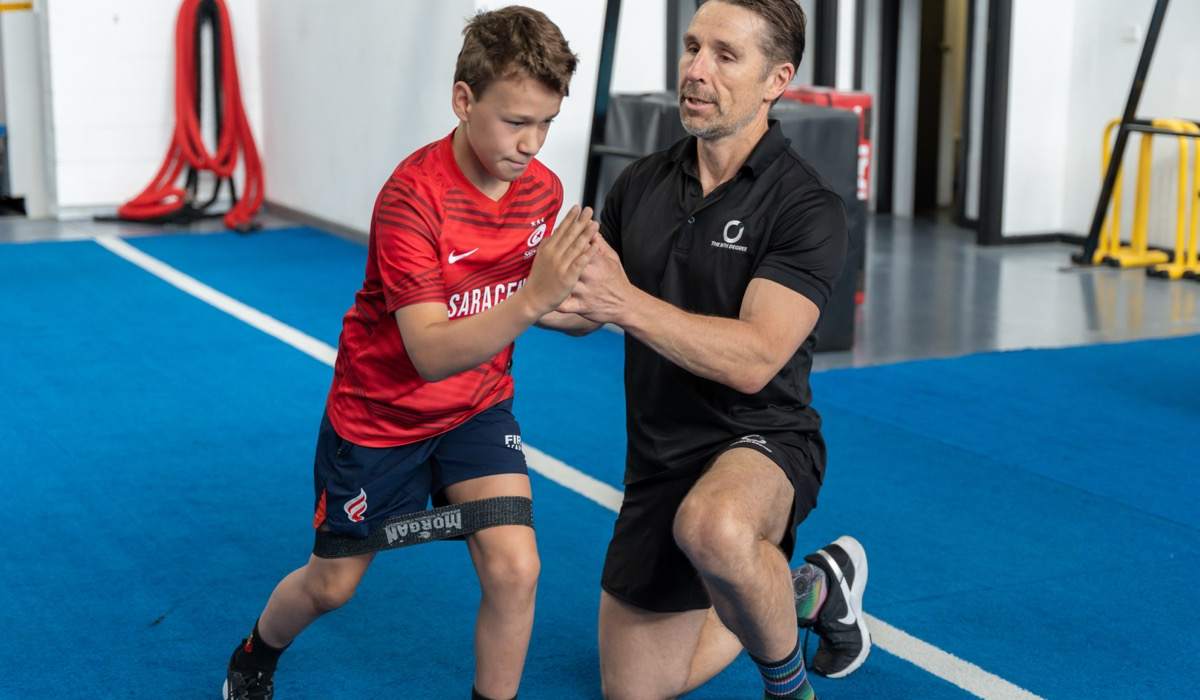 A coach working one-on-one with a young athlete on the turf at The Nth Degree, Norwood.